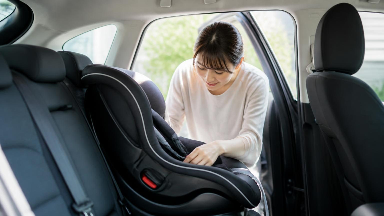 車の後部座席にチャイルドシートを取り付ける様子