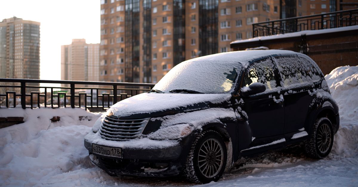 雪の朝にバッテリーを確認する車