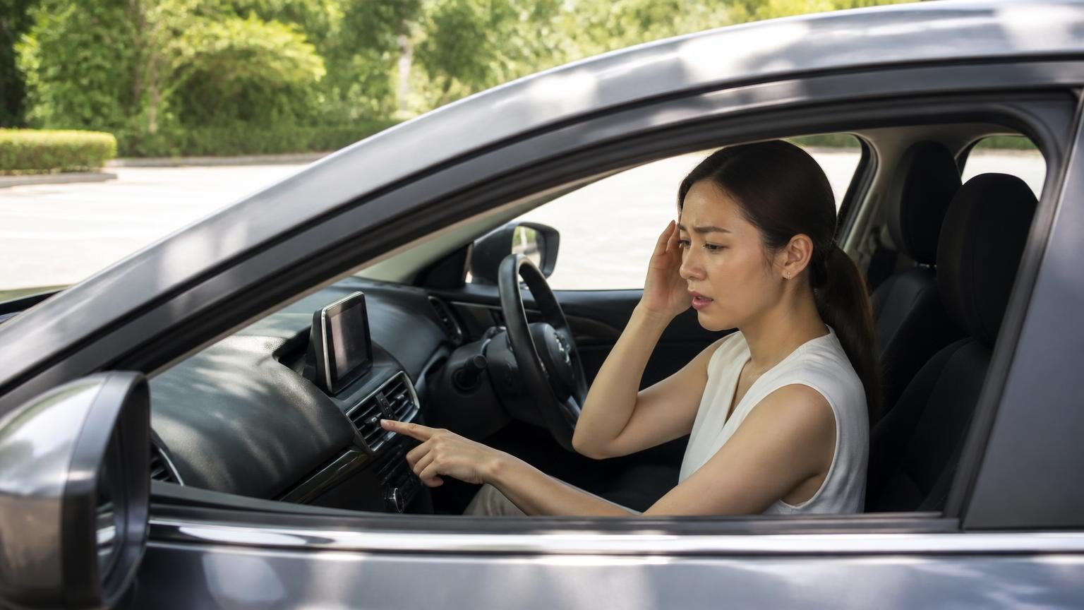 車のエアコン設定を確認する運転手